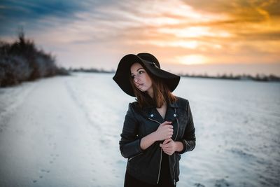 Portrait of a young woman standing against sunset