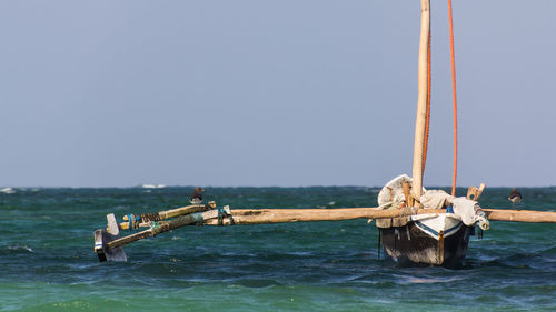 Boat sailing in sea against clear sky