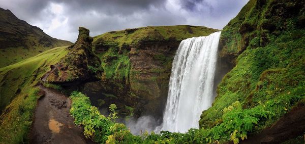Scenic view of skogafoss waterfall against cloudy sky