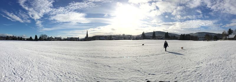 Panoramic view of snowy landscape against sky on sunny day