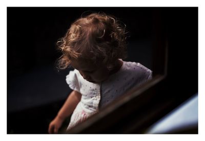 Woman looking away while sitting against black background