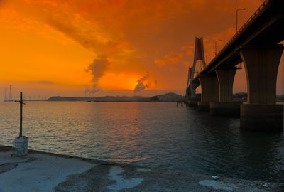 View of bridge over sea against orange sky