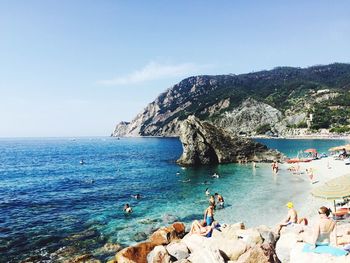 People enjoying at beach against sky