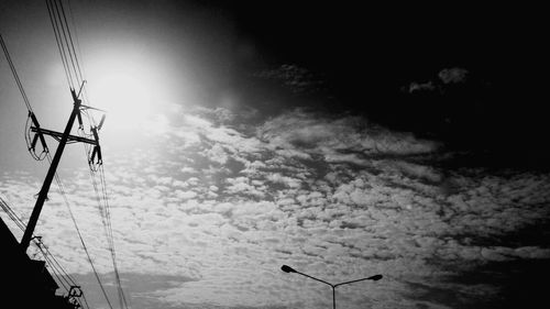 Low angle view of silhouette telephone pole against sky