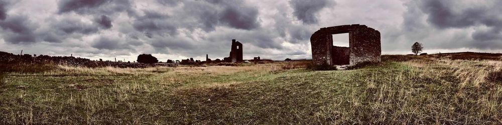 Panoramic view of old ruins on field against sky
