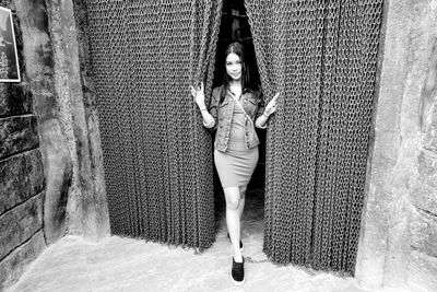 Portrait of young woman standing against wall