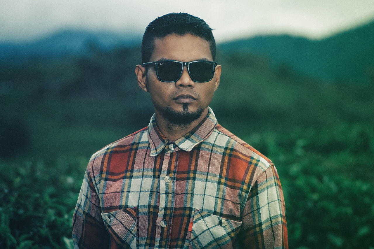 glasses, sunglasses, focus on foreground, fashion, young adult, portrait, real people, young men, standing, casual clothing, front view, one person, looking at camera, day, lifestyles, nature, land, leisure activity, outdoors