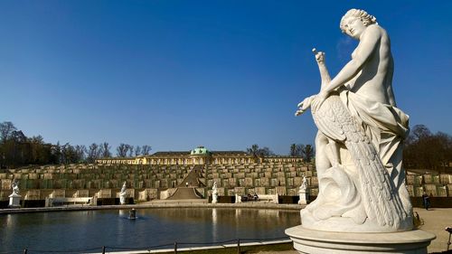 Statue and schloss sanssouci against clear blue sky