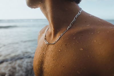 Person enjoying summer, with textures of water drops in his chest, wearing a chain.