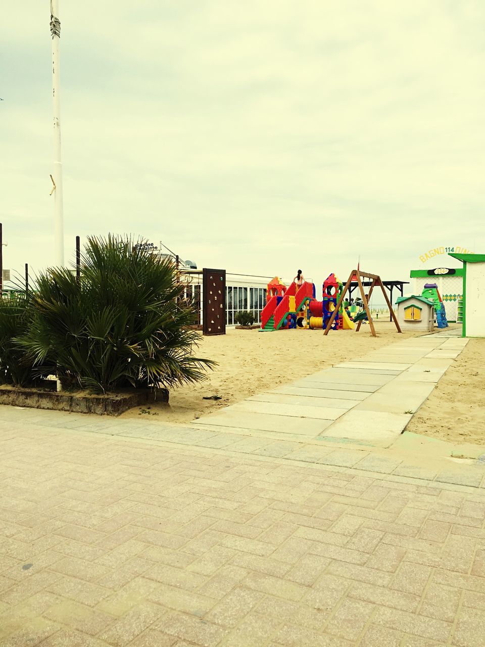 sky, built structure, architecture, building exterior, beach, sand, cloud - sky, sea, cloud, leisure activity, flag, day, lifestyles, men, incidental people, shore, tree, safety, outdoors