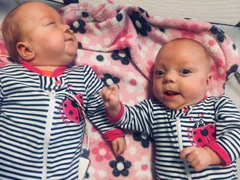 High angle view of cute baby girls lying on bed at home