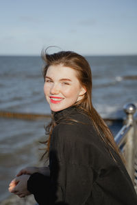 Portrait of young woman looking away against sea
