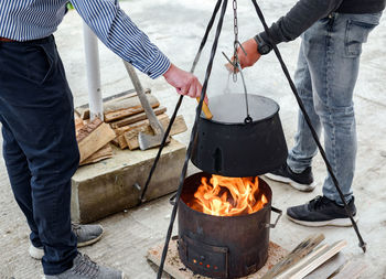 Friends cooking stew in cast iron boiler over fire