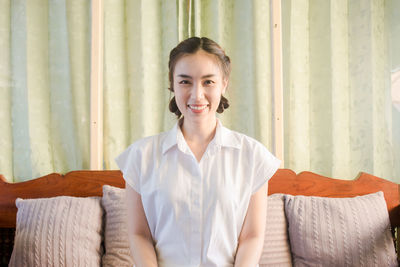 Portrait of smiling young woman relaxing on bed at home