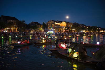 Boats in river against sky at night