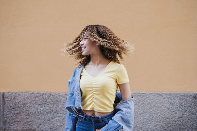 Happy woman standing against wall