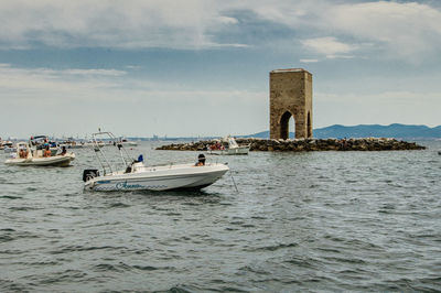 People on boat in sea against sky