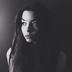 Close-up of a young thoughtful woman over plain background