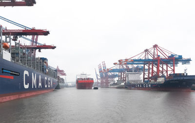 Cranes at harbor against sky