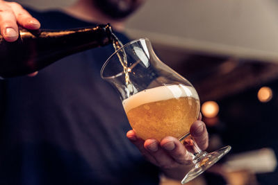 Midsection of man filling wineglass with beer