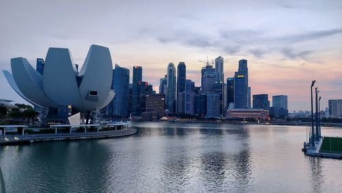 River by modern buildings against sky in city