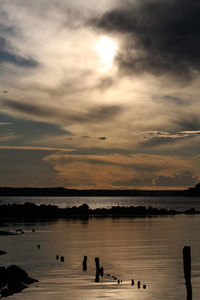 Silhouette people standing on lake against sky during sunset