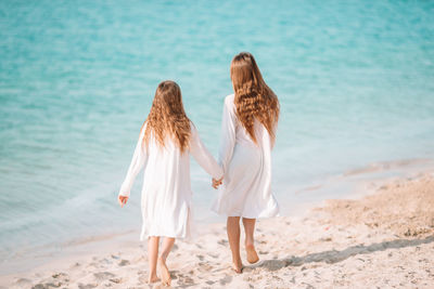 Rear view of women standing at beach