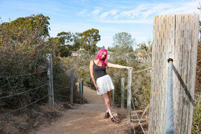 Woman standing on railing against trees
