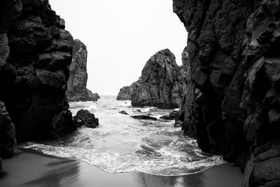 Rock formation on sea shore against sky