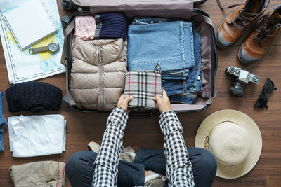 High angle view of man packing luggage at home