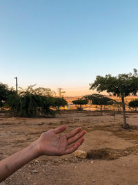 Midsection of person relaxing on land against clear sky