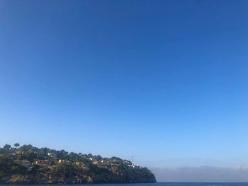 Scenic view of sea and buildings against clear blue sky