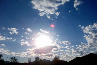 Low angle view of sun shining through clouds