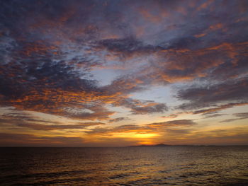 Scenic view of sea against dramatic sky during sunset