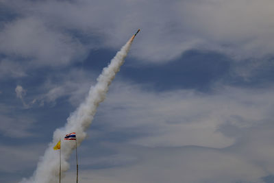 Low angle view of rocket flying against sky