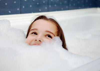 Girl playing with soap sud in bathtub