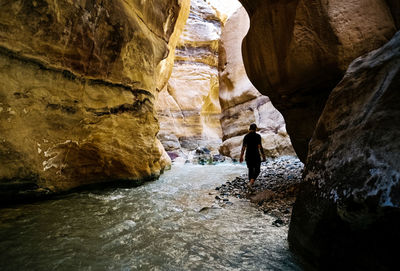 Rear view of woman standing in cave