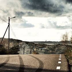 Empty road against cloudy sky