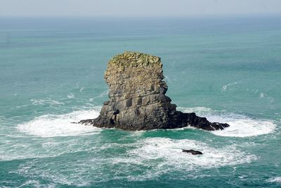 Rock formation in sea against clear sky