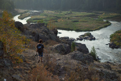 Rear view of man walking on rocks in water