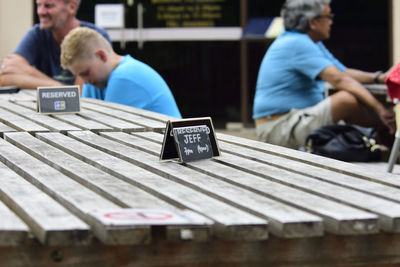 Close-up of label on table with people in background