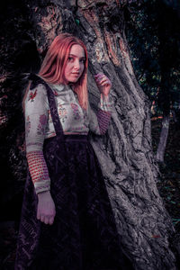 Portrait of woman with tree trunk in forest