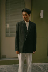 Portrait of young man standing against wall