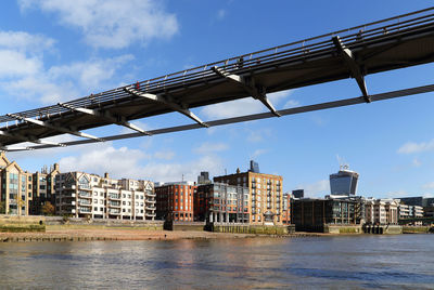 Low angle view of bridge over thames river against cloudy sky