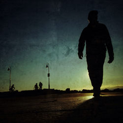 Silhouette of woman standing against sky at sunset