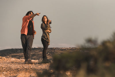 Friends standing on land against sky