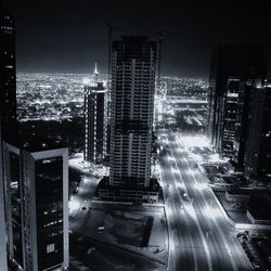 High angle view of illuminated street amidst buildings in city at night