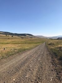 Road passing through landscape against clear sky