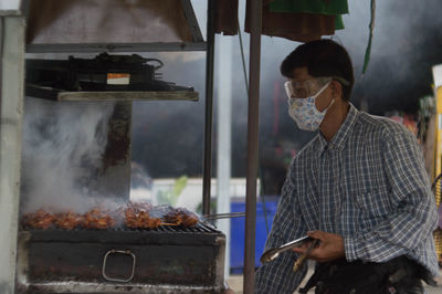 Man preparing meat on barbecue grill at market