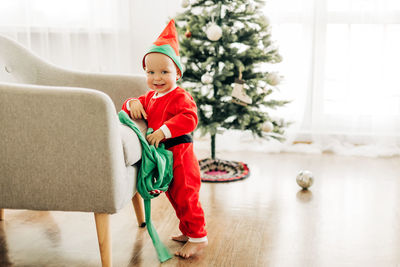 Portrait of cute boy standing by chair